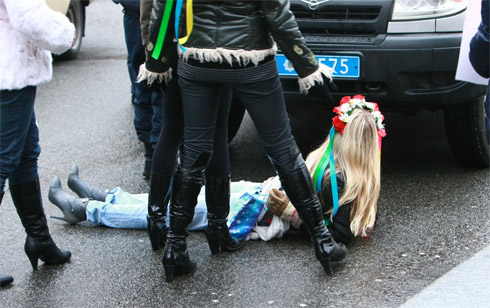 Активістка Femen Олександра Шевченко спробувала зупинити ментовське свавілля і лягла під колеса машини. Фото -  Артем Мірошенко